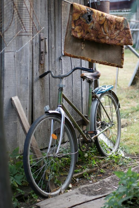 Old bicycle leaning on a village cabin.