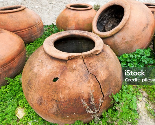 Partly broken pot lying on the ground next to other smaller pots.