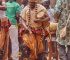 A photo of a man dressed in ethnic regalia beating w drum while dancing.