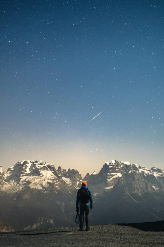 man standing,staring at a snow capped mountain.