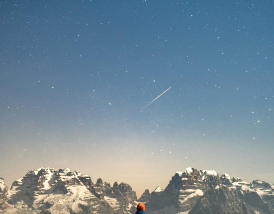 man standing,staring at a snow capped mountain.